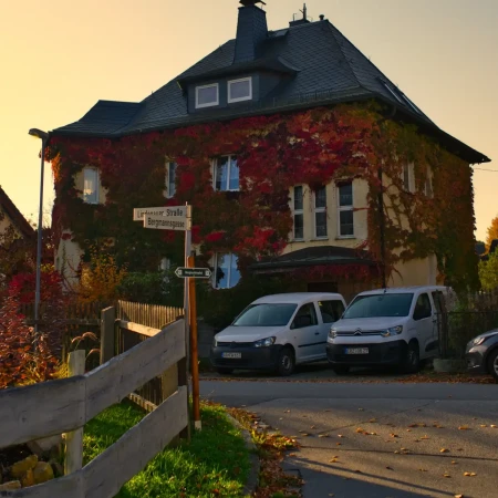 Das Haus hat einen Parkplatz direkt in der Einfahrt. Im Vordergrund weist ein Schild auf den Bergbaulehrpfad hin – perfekt als Ausganspunkt für spannende Ausflüge und Entdeckungen in der Stadt und der Umgebung. Ferienwohnung Hager am Bergbaulehrpfad