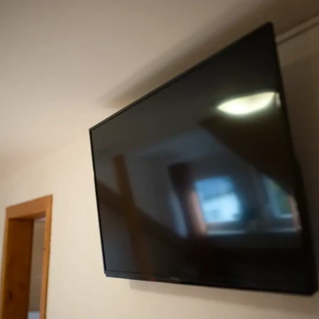 Der 40-Zoll-Smart-TV ist elegant an der Wand montiert und bietet Zugriff auf Streaming-Dienste, Apps und mehr. Perfekt für entspannte Filmabende oder den schnellen Zugriff auf Unterhaltung nach einem erlebnisreichen Tag.