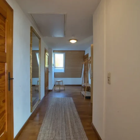 Der Flur mit elegantem Ganzkörperspiegel, Garderobe und praktischem Bambus-Sitzhocker zum Schuheanziehen