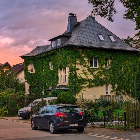 Das mit wildem Wein bewachsene Haus strahlt in der Abenddämmerung eine besondere Atmosphäre aus. Die natürliche Begrünung verleiht dem Gebäude einen charmanten, einladenden Charakter – ein idyllischer Ort, um zur Ruhe zu kommen.